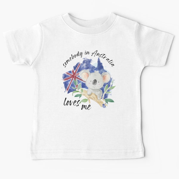 White childrens sized tshirt with somebody in Australia loves you written in cursive text around the picture of a grey koala sitting on the branch of a gumtree on the background of the australian flag